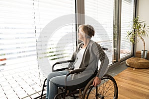 Disabled senior woman in wheelchair at home in living room.