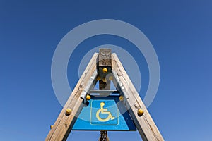 Disabled sign and simbol on wooden swing pole, playground with c