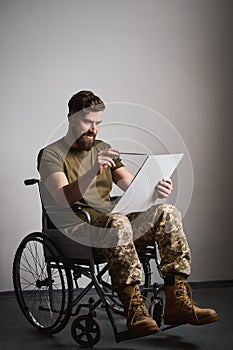 Disabled soldier sitting in a wheelchair and painting on a canvas