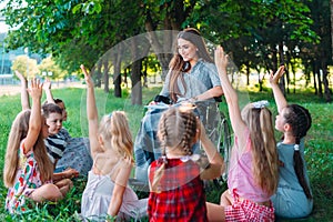 Disabled teacher conducts a lesson with children in nature. Interaction of a teacher in a wheelchair with students.