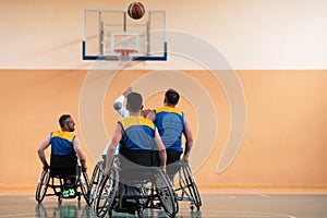 Disabled War veterans mixed race and age basketball teams in wheelchairs playing a training match in a sports gym hall