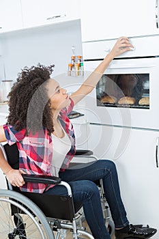 Disabled woman baking bread roll in kitchen oven