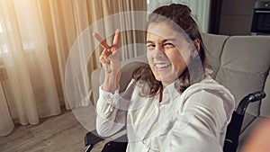 Disabled woman makes fingers Victory sign smiling to camera