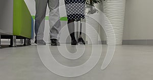 A disabled woman on a prosthesis walks next to a doctor in the clinic. Legs in close-up.