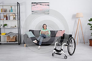 Disabled woman reading book near wheelchair