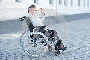 Disabled woman sitting outside and waving