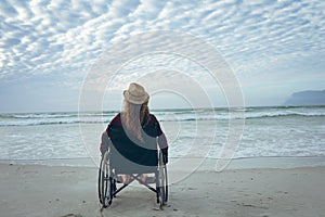 Disabled woman sitting on wheelchair at beach