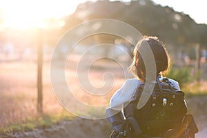 A disabled woman standing outside looking at the sunset reflecting