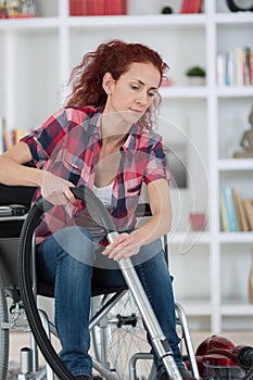 Disabled woman using vacuum cleaner at home