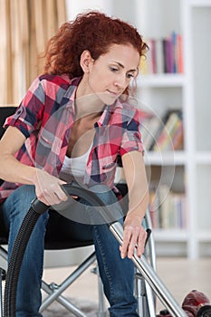 Disabled woman using vacuum cleaner at home