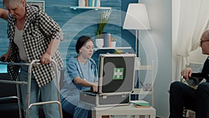 Disabled woman walking with walk frame while nurse giving assistance