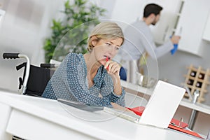 Disabled woman in wheelchair at desk