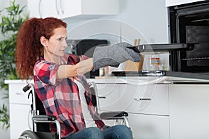 Disabled woman in wheelchair preparing meal in kitchen