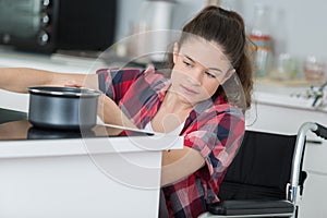 Disabled woman in wheelchair preparing meal in kitchen