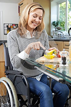 Disabled Woman In Wheelchair Preparing Meal In Kitchen