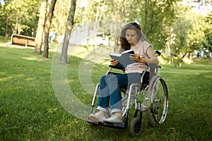Disabled woman in wheelchair reading book in park