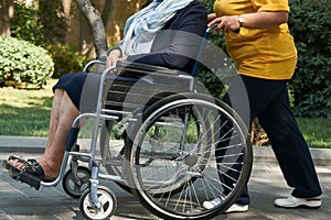 Disabled woman in a wheelchair relaxing in a park with a care assistant