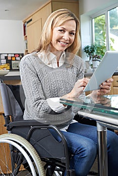 Disabled Woman In Wheelchair Using Digital Tablet At Home