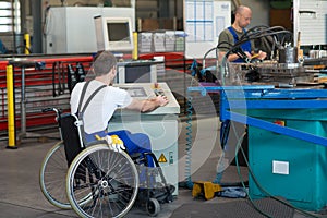 Disabled worker in wheelchair in factory and colleague