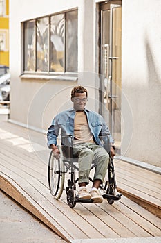Young man in wheelchair moving down ramp