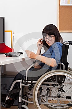 Disabled young girl on wheelchair working in her office