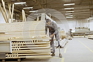 Disabled young man with artificial leg is working at the furniture factory