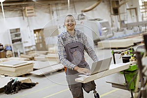 Disabled young man with an artificial leg is working at the furniture factory