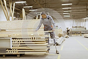 Disabled young man with an artificial leg is working at furniture factory