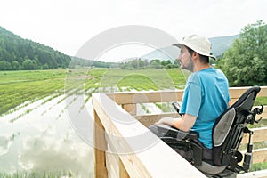 Disabled Young man in electric wheelchair on a boardwalk enjoying his freedom and observing nature