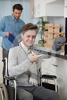 Disabled young man in wheelchair opens oven