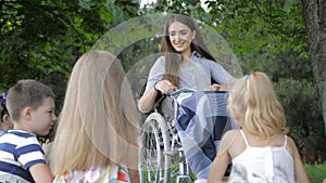 Disabled young teacher reading book to boys and girls in park