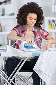 Disabled young woman ironing in living room