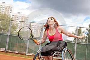 Disabled young woman on wheelchair playing tennis on tennis court.