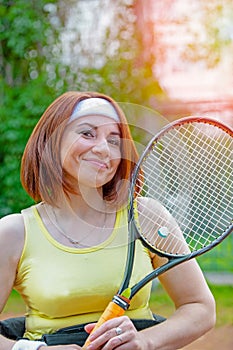 Disabled young woman on wheelchair playing tennis on tennis court.