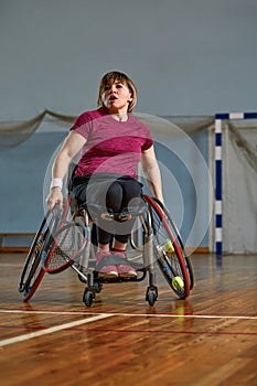 Disabled young woman on wheelchair playing tennis on tennis court