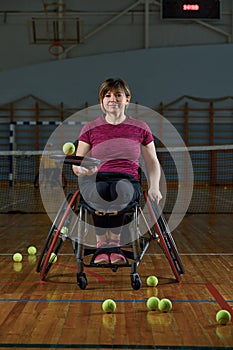 Disabled young woman on wheelchair playing tennis on tennis court
