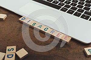 Disagree word written on wooden letter cubes tiles - computer desk and keyboard