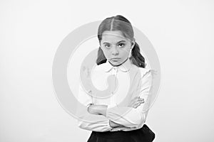 Disagreement and stubbornness. Girl school uniform serious face offended yellow background. Kid unhappy looks strictly photo