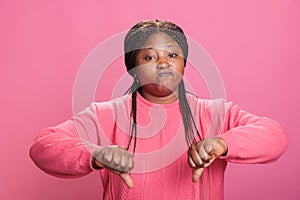 Disappointed african american model showing thumbs down symbol in studio