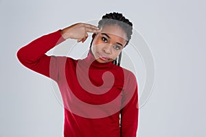 Disappointed Afro American girl holding two fingers near her temple.