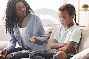Disappointed black mother looking at her little daughter with reproach photo