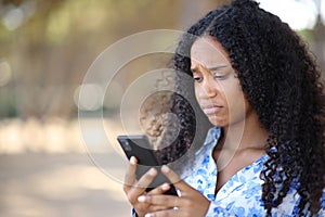 Disappointed black woman using cell phone