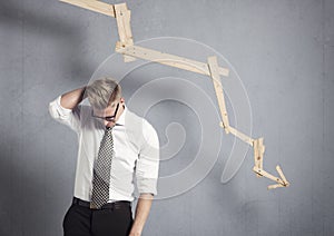 Disappointed businessman in front of graph pointing down.