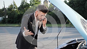 Disappointed businessman solving problem of a broken car insurance auto.
