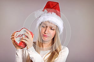 Disappointed Christmas woman with a Santa hat holding a gift box