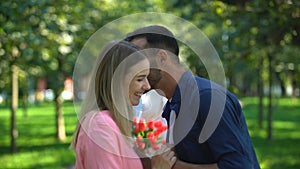 Disappointed man with flowers watching his girlfriend kissing with another man