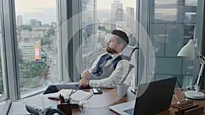 Disappointed manager reading message on smartphone sitting in luxury office.