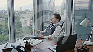 Disappointed manager reading message on smartphone sitting in luxury office.