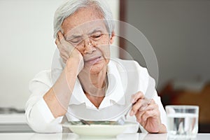 Disappointed old elderly people eating overnight food,she`s sick of food,tired of eating same food,lacking flavor,Asian senior photo