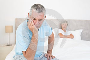 Disappointed senior man with woman in background photo